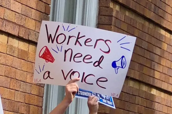 Worker holding a sign that says "Workers need a voice"